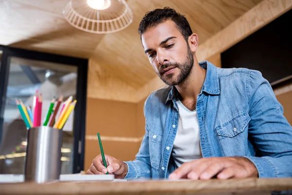 Man in office writing in a notepad — Stock Photo, Image