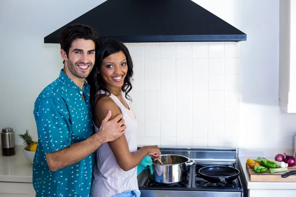 Man omhelst vrouw tijdens het koken — Stockfoto