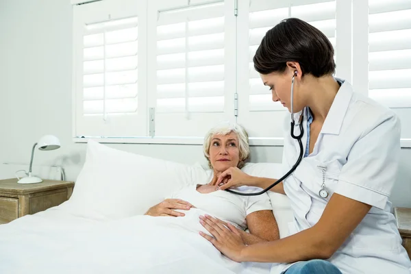 Mujer médico auscultating mujer —  Fotos de Stock