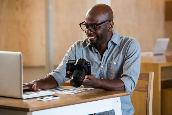 Man holding camera using laptop — Stock Photo, Image