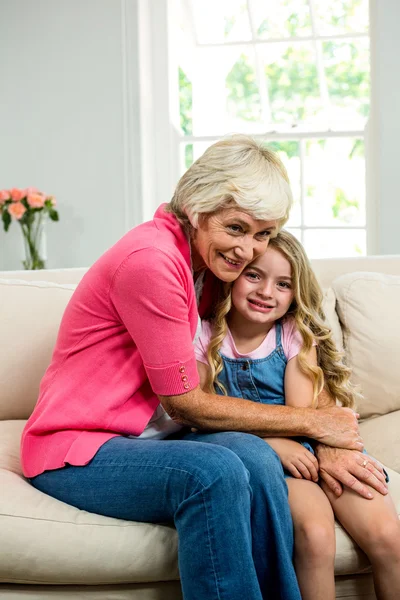 Abuelita y chica abrazo sentado en sofá — Foto de Stock