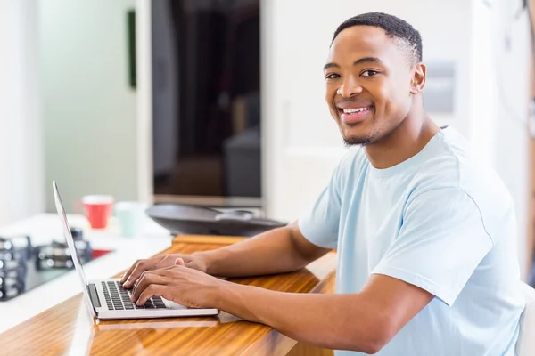 Young man using laptop in kitchen — Stock Photo, Image