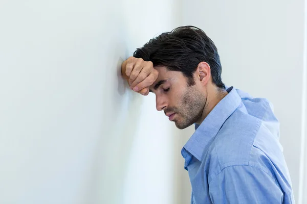 Depressiver Mann lehnt Kopf gegen Wand — Stockfoto