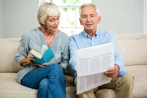 Pareja mayor leyendo el periódico en casa — Foto de Stock