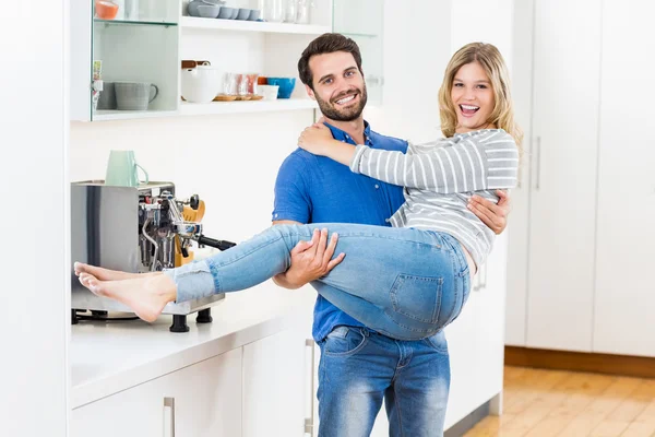 Homme levant femme dans les bras dans la cuisine — Photo