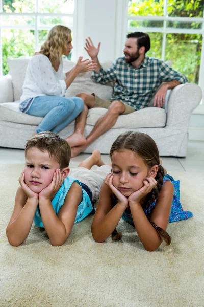 Niños mintiendo contra padres luchando — Foto de Stock