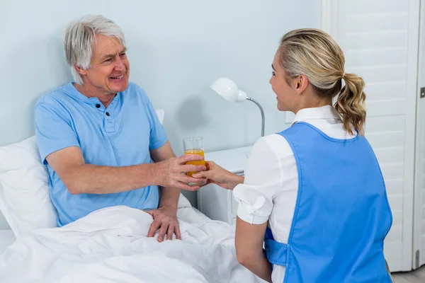 Enfermeira dando suco ao homem sênior — Fotografia de Stock