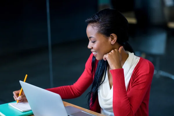 Mujer joven sentada en su escritorio — Foto de Stock