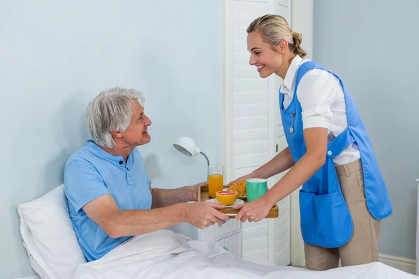 Enfermeiro que oferece café da manhã ao homem idoso — Fotografia de Stock