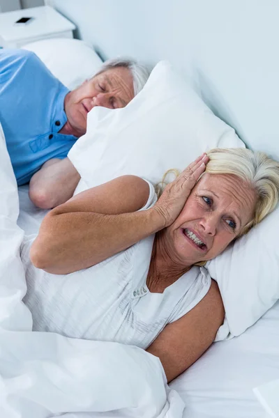 Vrouw die betrekking hebben op oren terwijl man snurken — Stockfoto