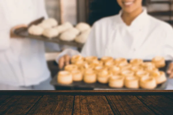 Panadero sonriendo a la cámara y sosteniendo bandeja — Foto de Stock