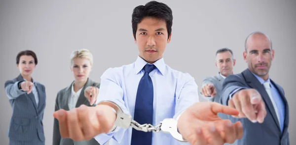 Businessman with handcuffs with people pointing — Stock Photo, Image