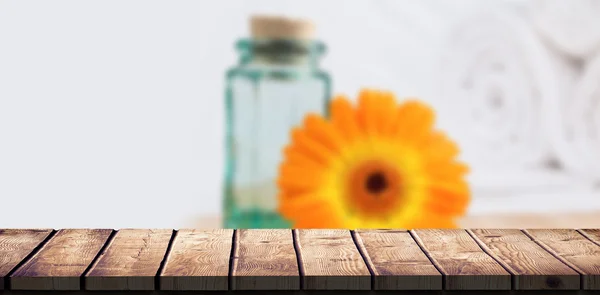 Mesa de madeira contra frasco e flor de laranja — Fotografia de Stock