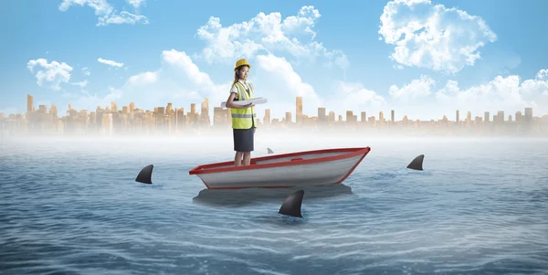 Architect woman in boat against sharks — Stock Photo, Image