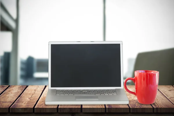 Portátil con taza roja en el escritorio —  Fotos de Stock