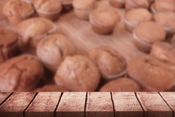 Houten bureau tegen muffins op teller — Stockfoto