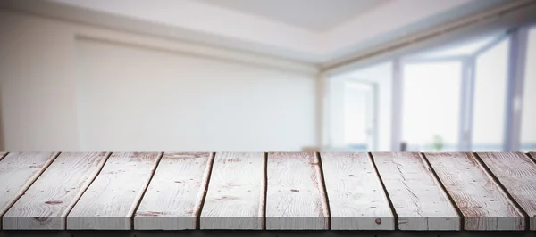 Tavolo in legno contro camera bianca — Foto Stock