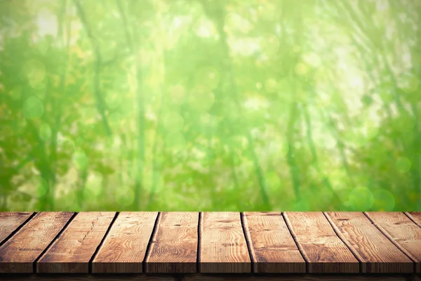 Wooden table against green forest — Stock Photo, Image