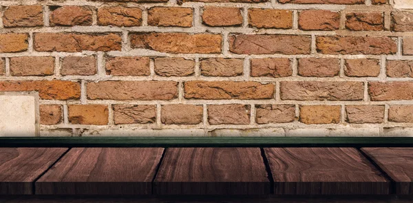 Wooden table against bricks wall — Stock Photo, Image