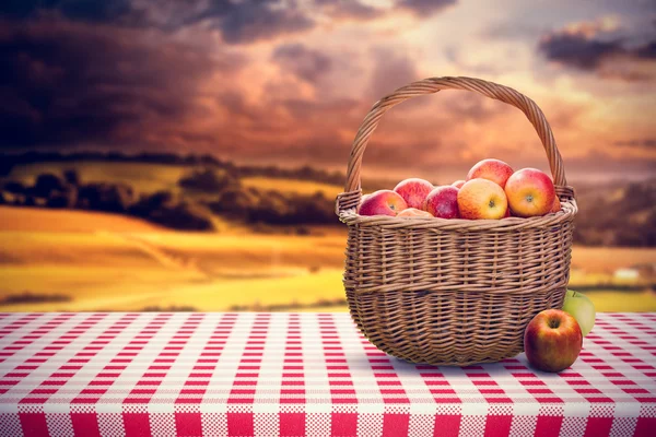 Basket of apples against country scene — Stock Photo, Image