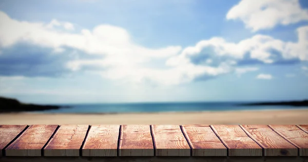 Wooden desk against beach with sky — Stock Photo, Image