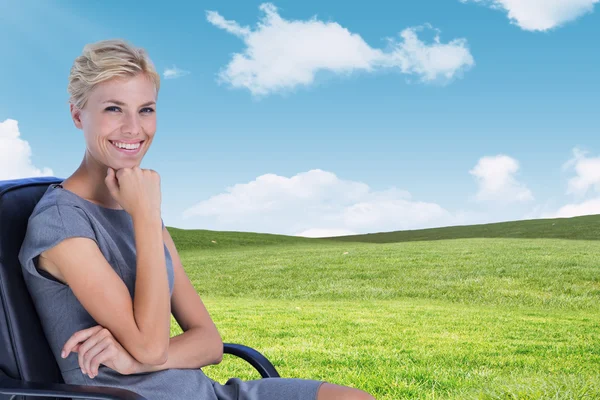 Businesswoman sitting on chair with hand on chin — Stock Photo, Image