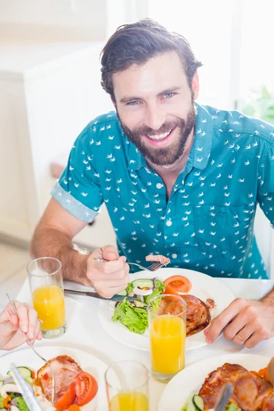 Ung man sitter vid matbordet leende — Stockfoto