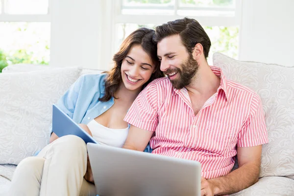 Pareja usando tableta digital y portátil en la sala de estar —  Fotos de Stock