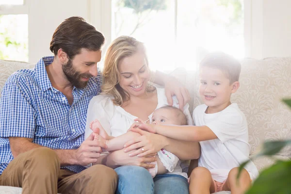 Padres sentados en el sofá con sus hijos — Foto de Stock