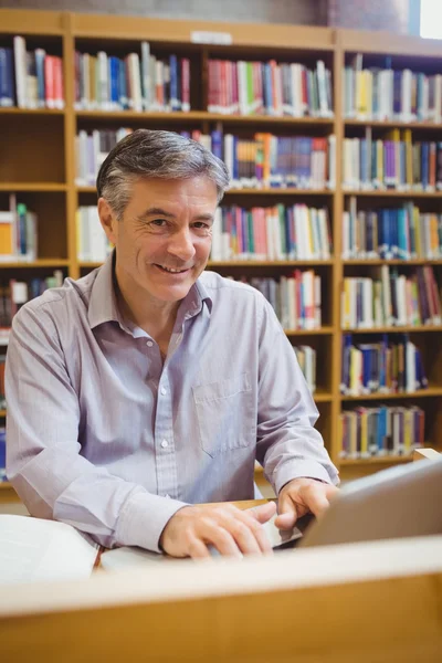 Portrait de professeur heureux assis au bureau à l'aide d'un ordinateur portable — Photo