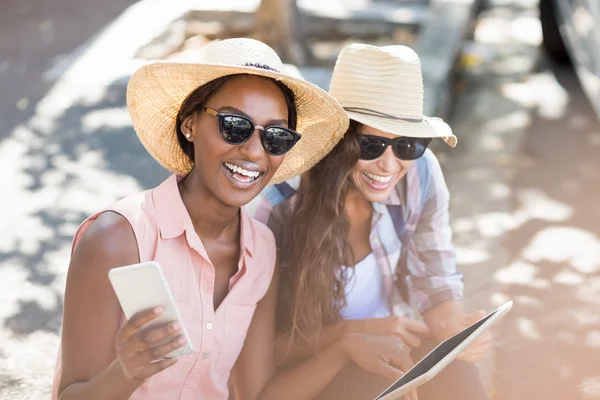 Mujeres jóvenes usando tableta digital y teléfono móvil —  Fotos de Stock