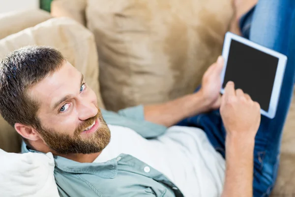 Retrato del hombre acostado en el sofá y el uso de tableta digital —  Fotos de Stock