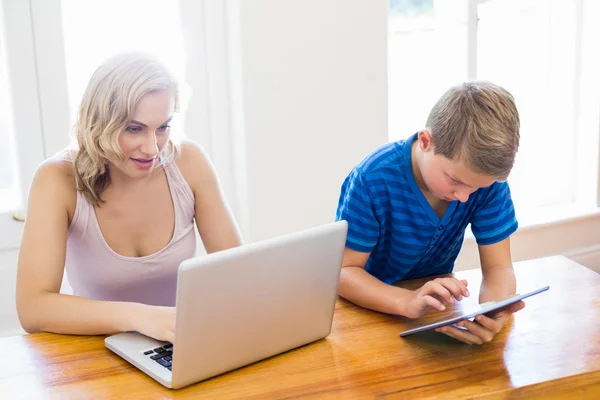 Lycklig mor och son med laptop och digital tablet — Stockfoto