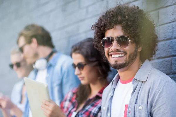 Jeune homme en lunettes de soleil souriant à la caméra — Photo