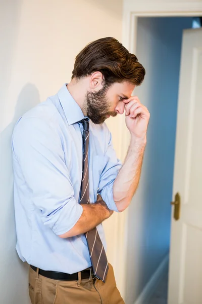 Worried man with hand on forehead leaning on wall — Stock Photo, Image