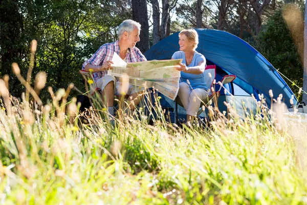 Ältere Paare lächeln und lesen eine Landkarte — Stockfoto