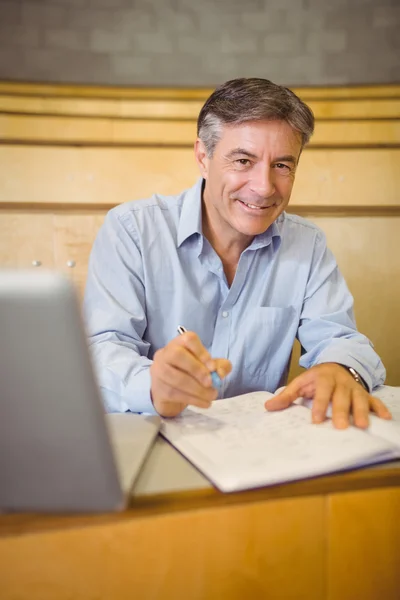 Портрет счастливого профессора, пишущего в книге за столом — стоковое фото