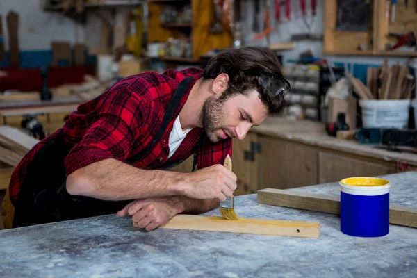 Carpenter painting a piece of wood — Stock Photo, Image