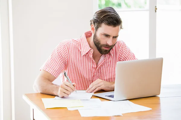 Jongeman laptop gebruikt tijdens het berekenen van een rekeningen — Stockfoto