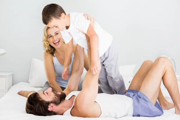 Pais e filho se divertindo na cama no quarto — Fotografia de Stock