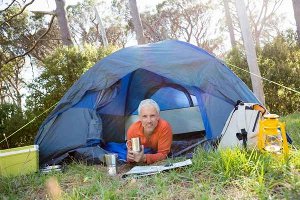 Älterer Mann lächelt und hält einen Becher in der Hand — Stockfoto