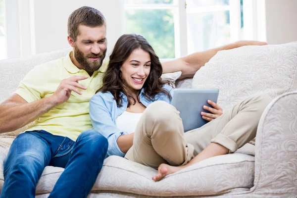 Paar sitzt auf Sofa und nutzt digitales Tablet im Wohnzimmer — Stockfoto