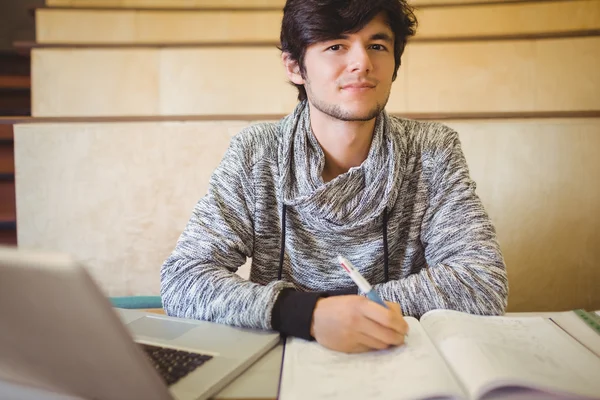Портрет молодого студента, сидящего на столе и читающего заметки — стоковое фото