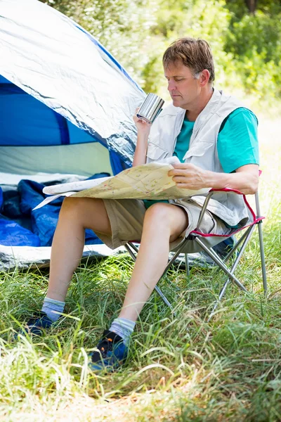 Homem sênior lendo ao lado de sua tenda — Fotografia de Stock