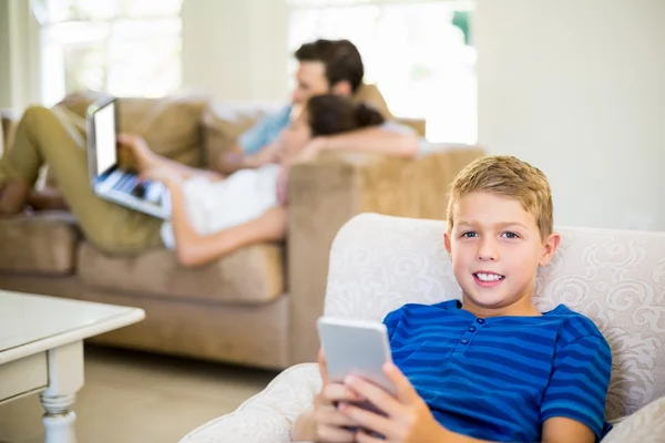 Garçon assis sur le canapé et utilisant un téléphone mobile — Photo