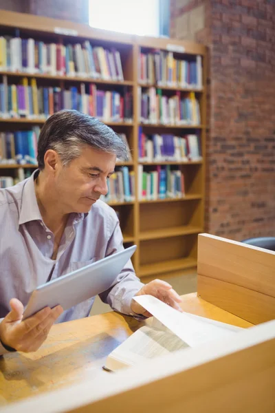 Professor holding digital tablet and reading book — Stock Photo, Image