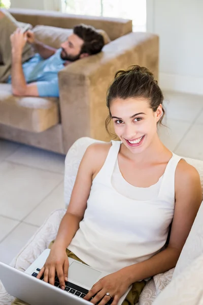 Femme à l'aide d'un ordinateur portable tandis que l'homme couché dans backgroud — Photo