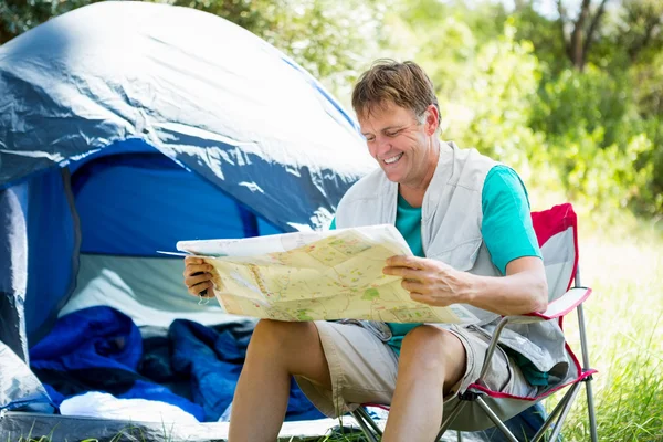 Senior man reading beside his tent — Stock Photo, Image