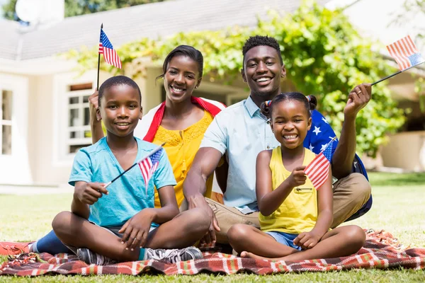 Счастливая семья показывает нам флаг Лицензионные Стоковые Изображения