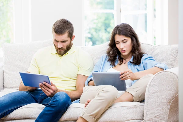Пара сидит на диване и с помощью цифрового планшета — стоковое фото